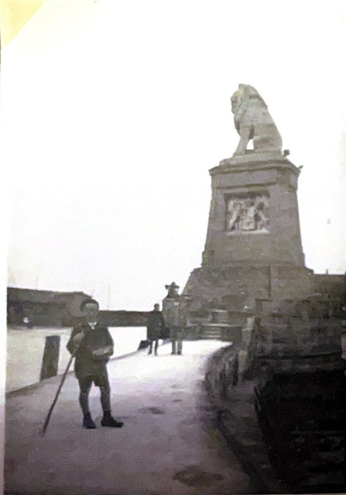 Junge mit Stock an einer Hafenmole mit Löwenstatue